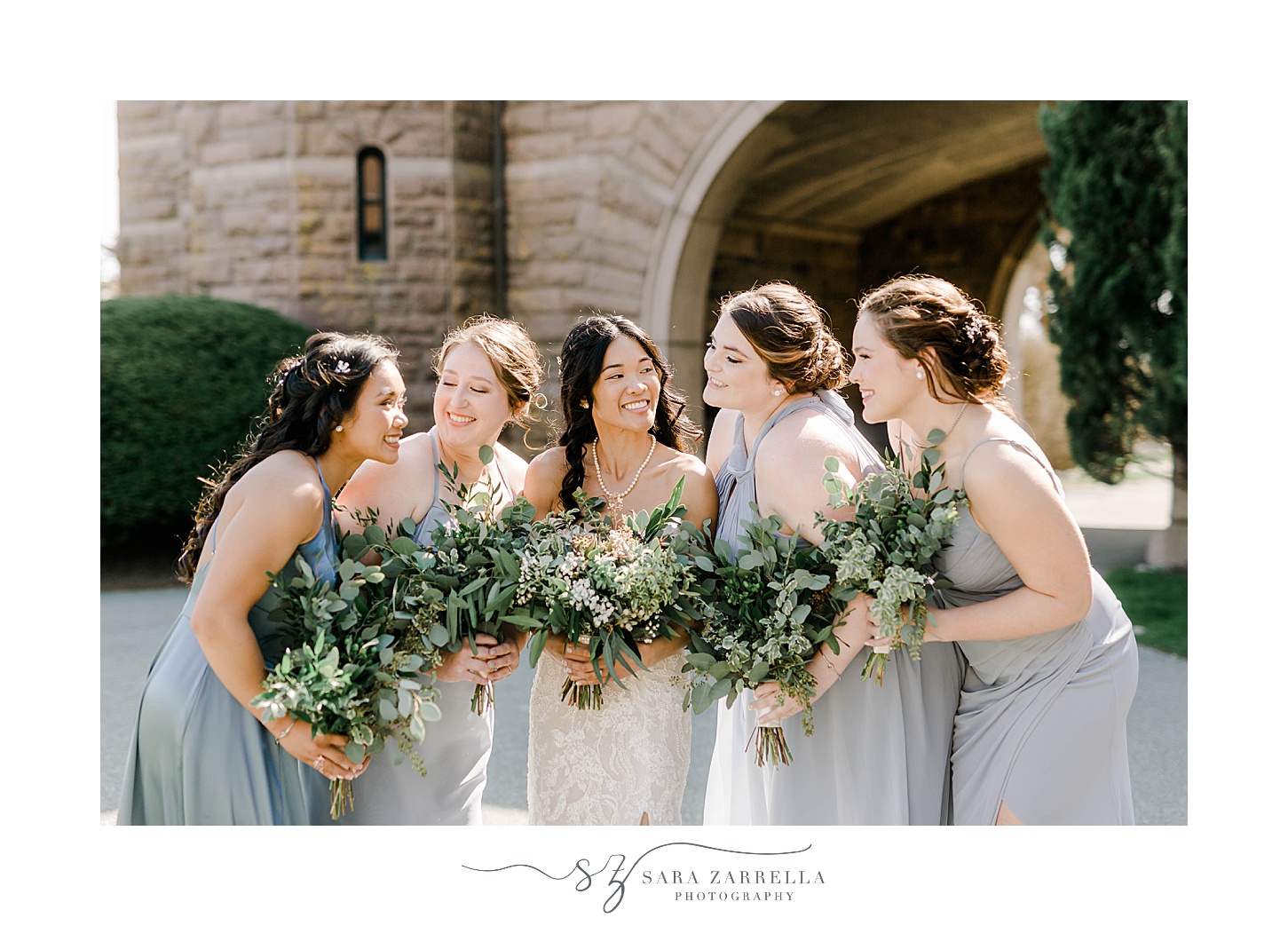 bride smiles at bridesmaids in light blue gowns with succulent bouquets 