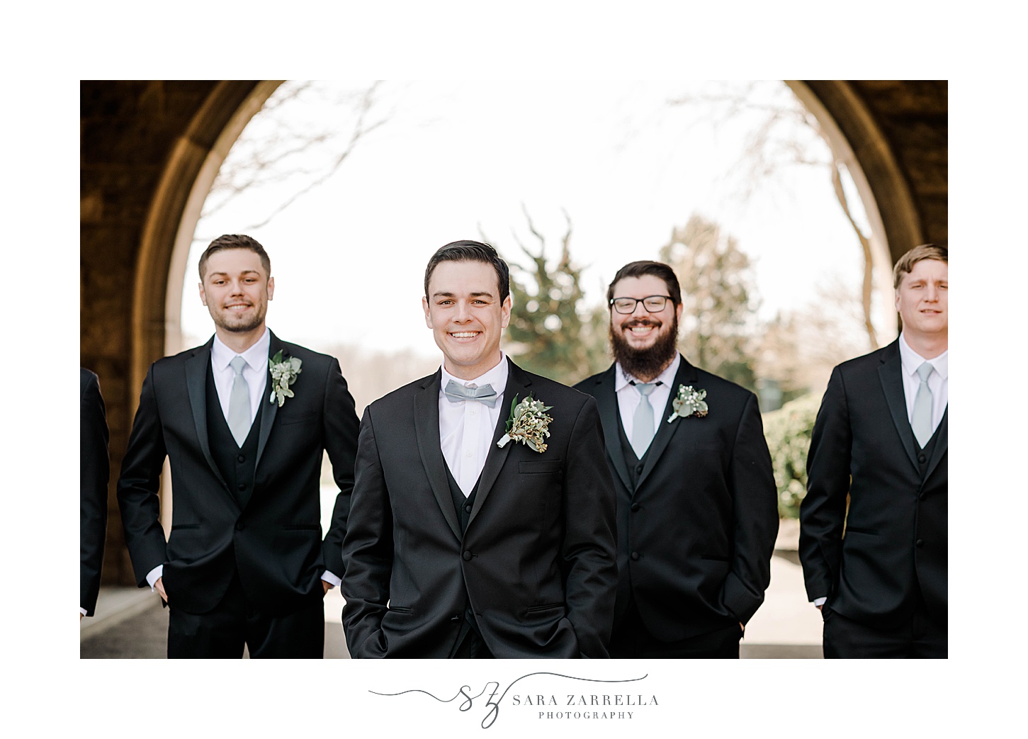 groom and groomsmen walk in black jackets with blue ties 