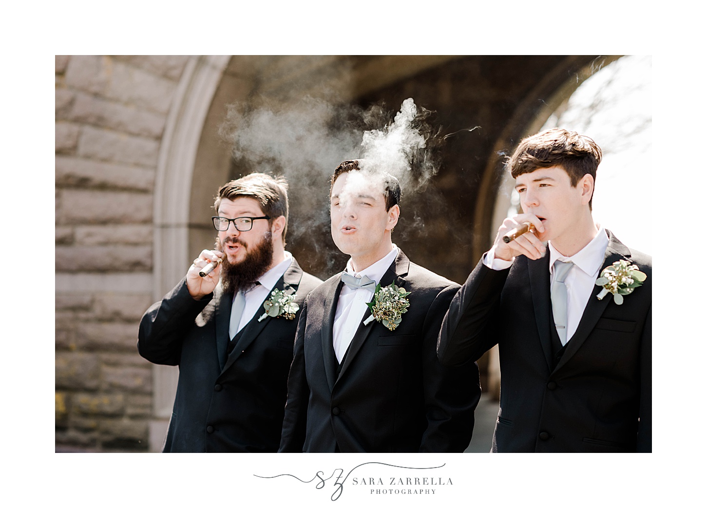 groom and groomsmen blow smoke from cigars 