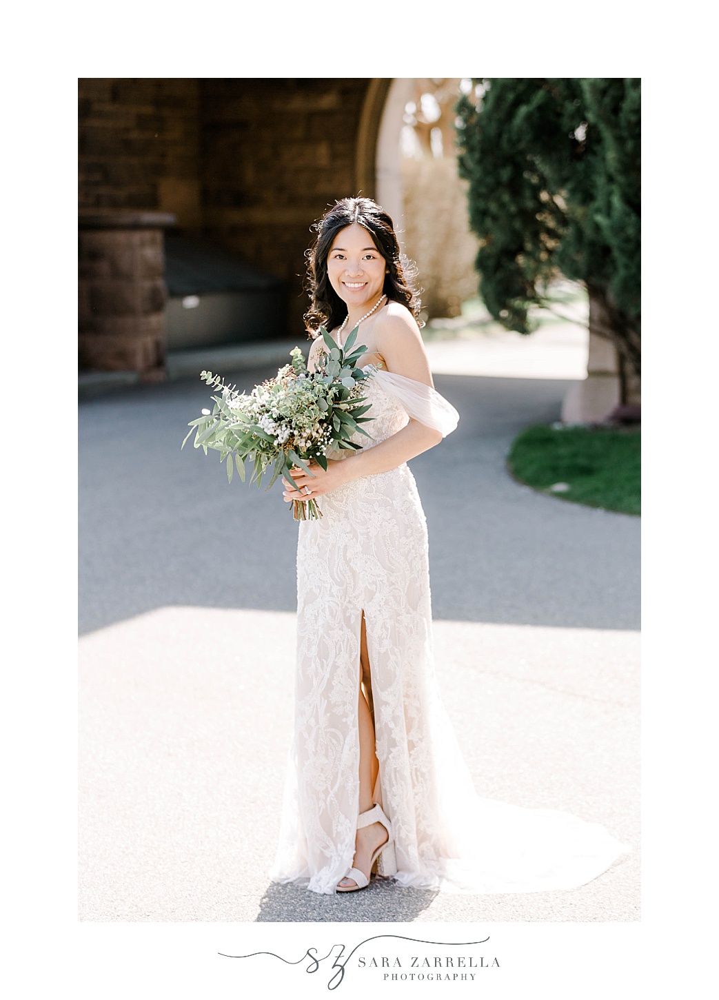 bride stands in chic off-the-shoulder wedding gown with slit near leg and succulent bouquet 