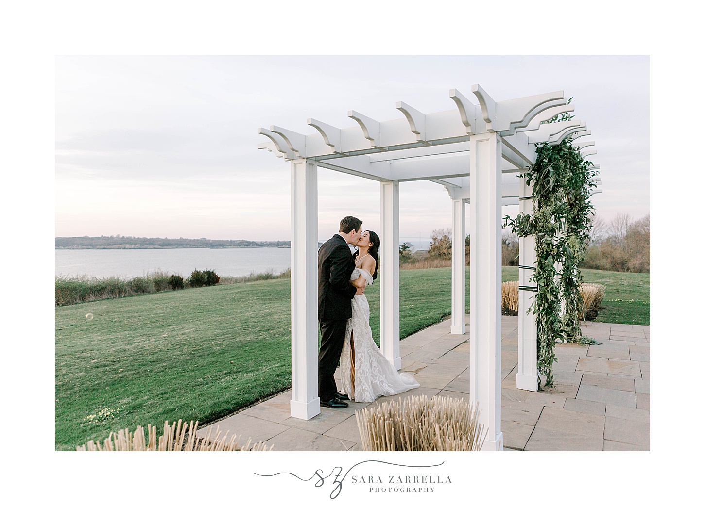 newlyweds kiss under white arbor at OceanCliff Hotel 