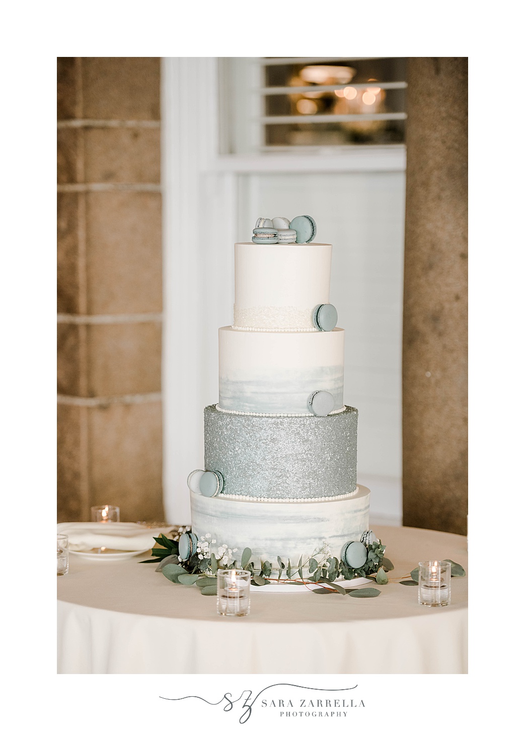 tiered wedding cake with metallic blue bottom layer and macrons on top