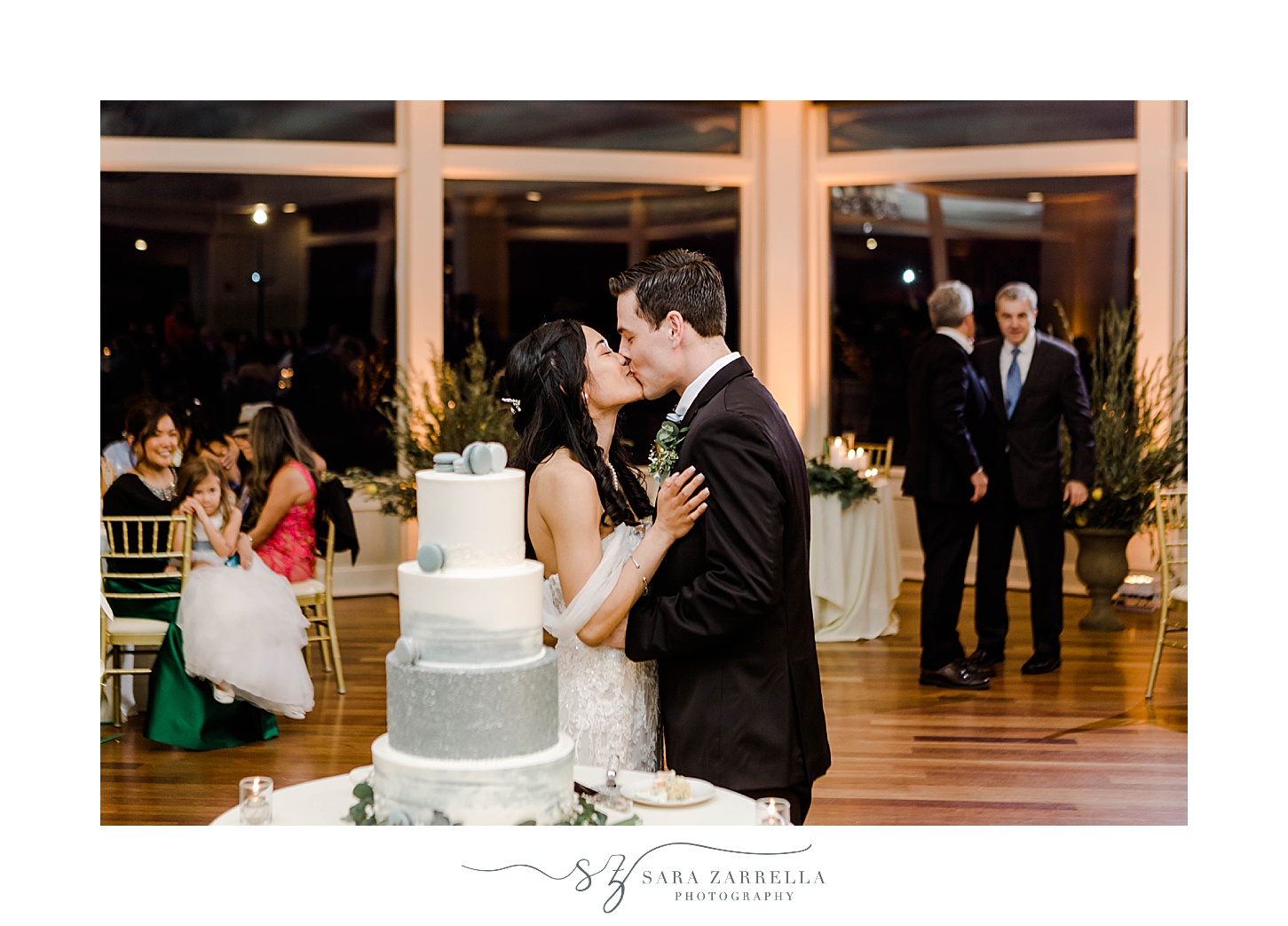 newlyweds kiss by wedding cake at wedding reception in Newport RI