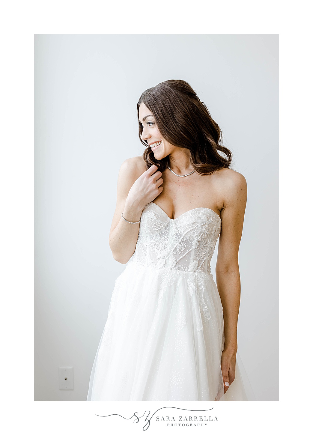 bride smiles over shoulder in strapless wedding gown