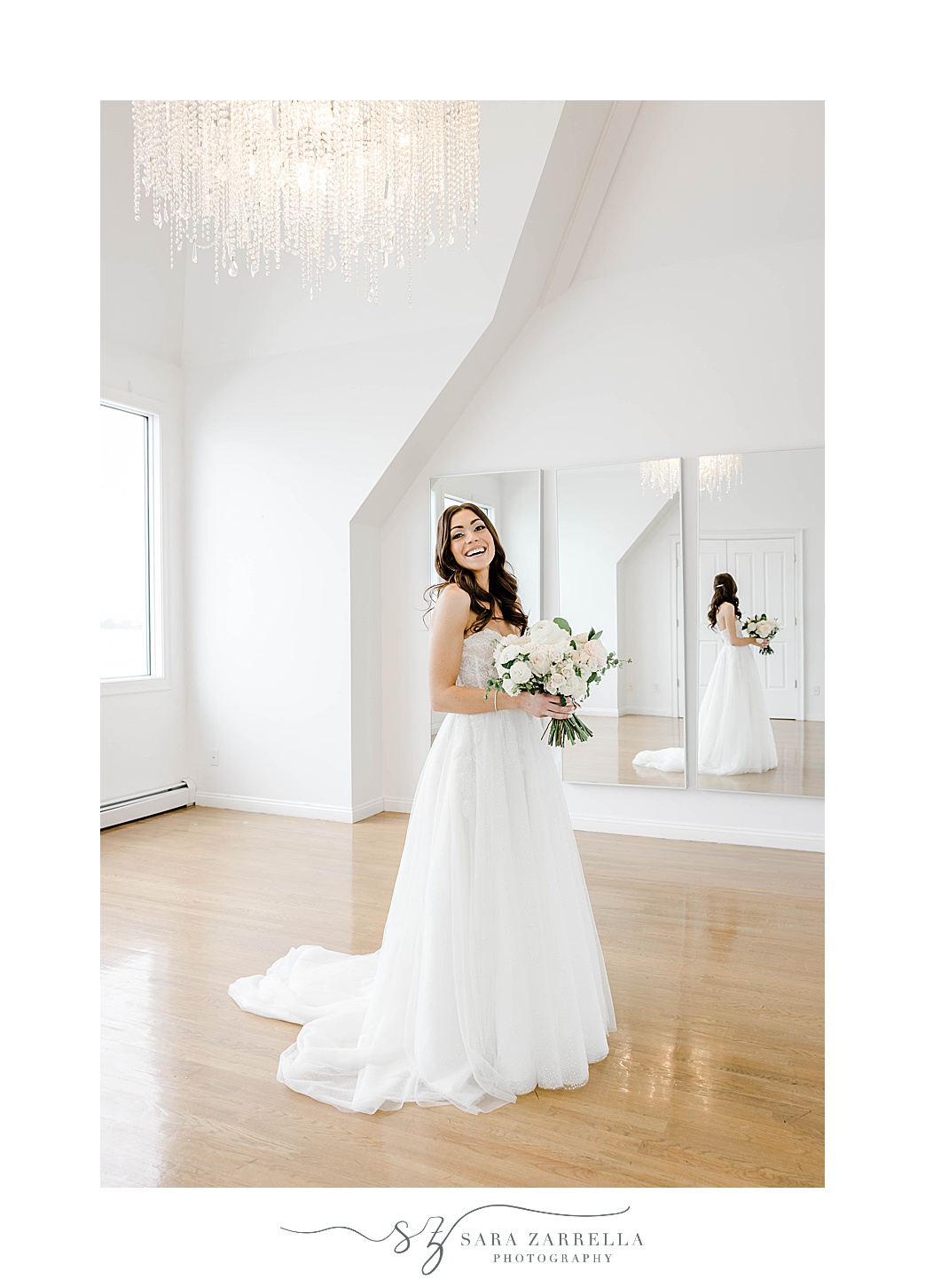 bride turns in wedding dress holding ivory rose bouquet by mirror 