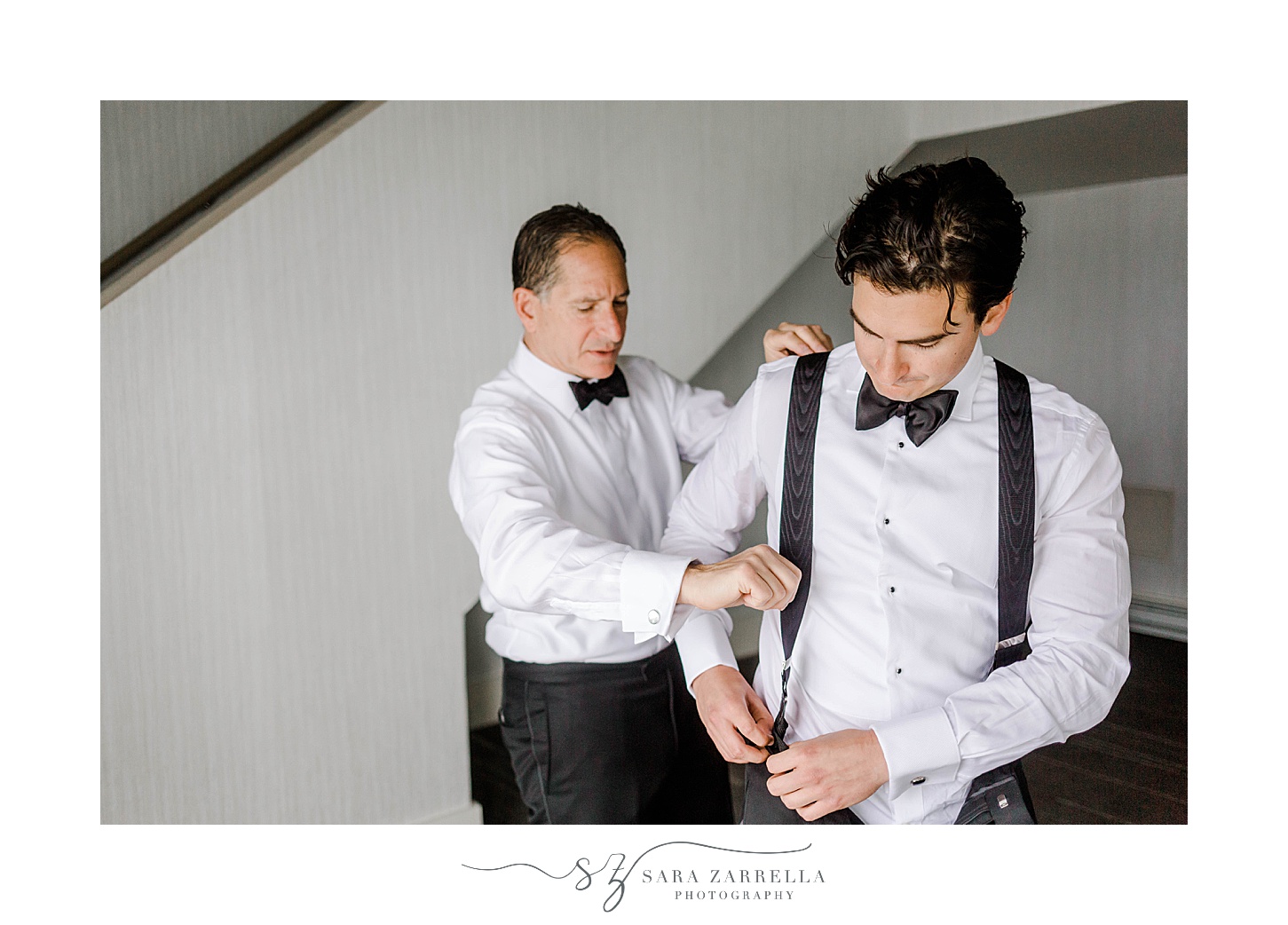 groomsman helps groom into jacket and with suspenders 