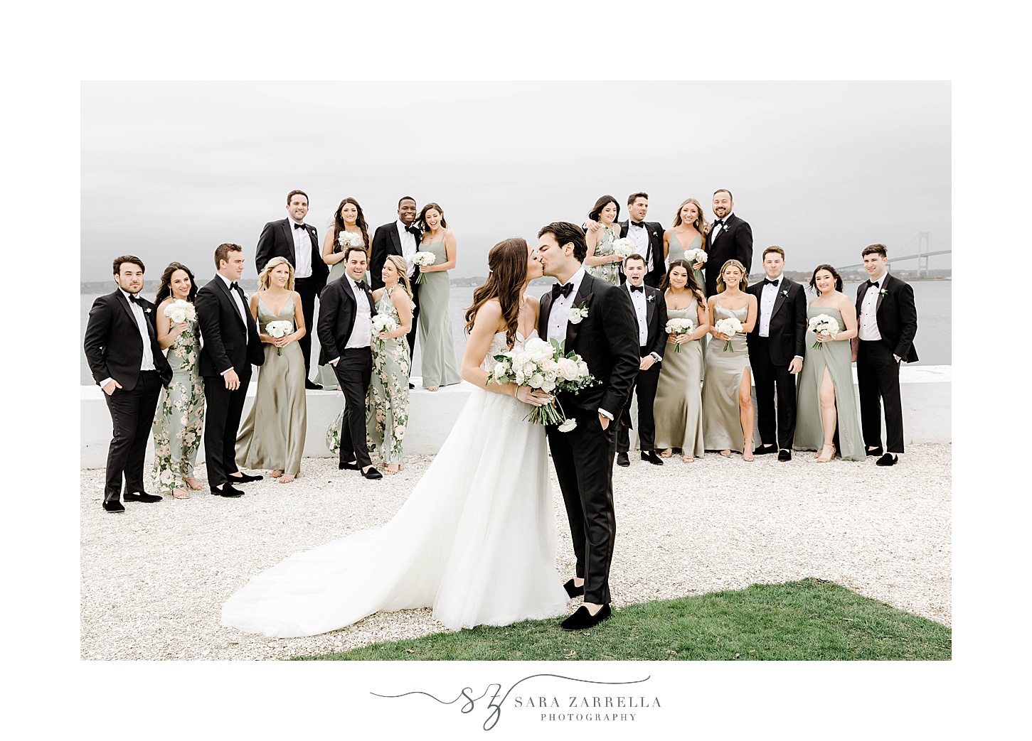bride and groom kiss with wedding party around them at Belle Mer Island House