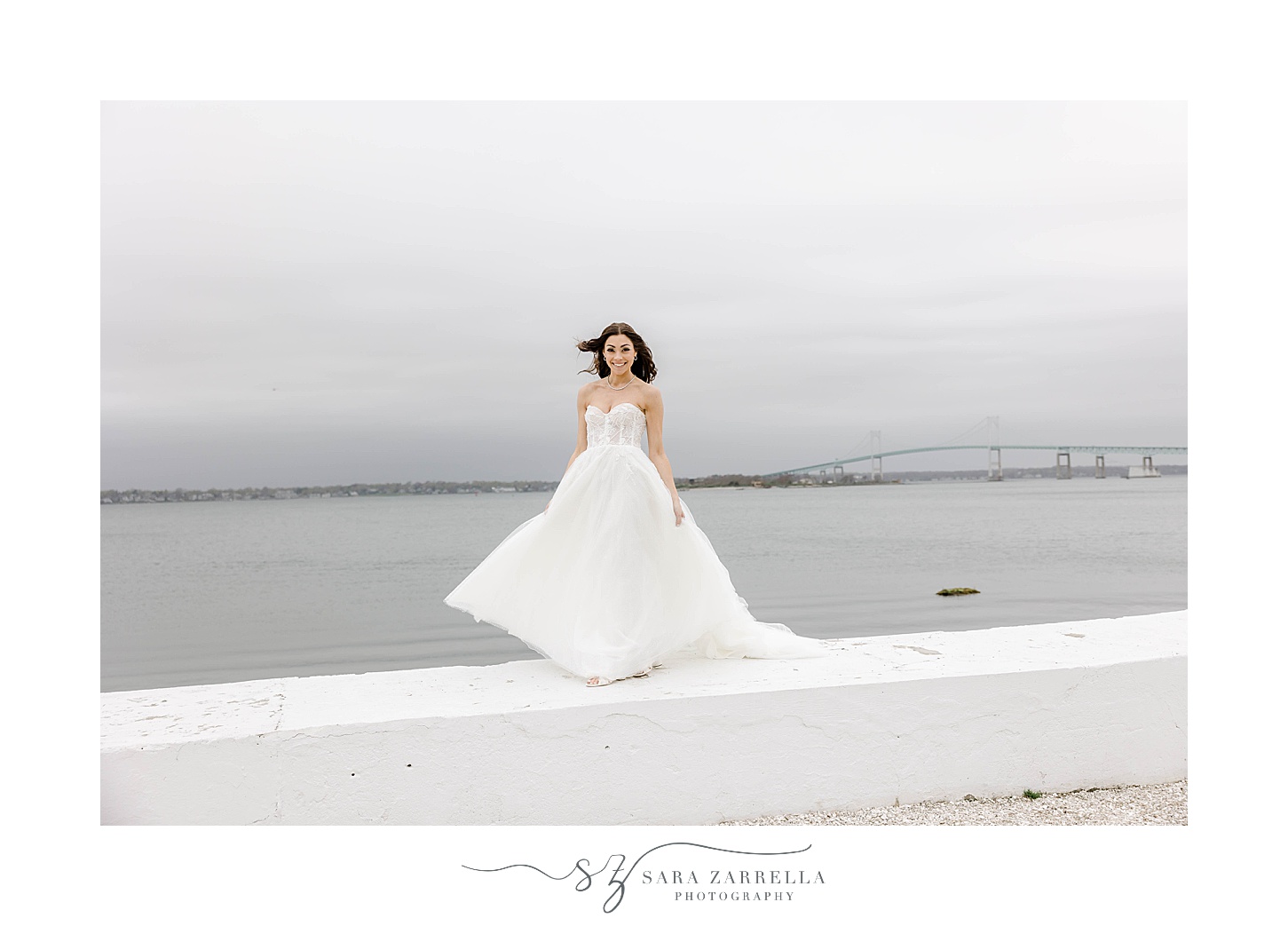 bride stands on white wall near Newport Bridge