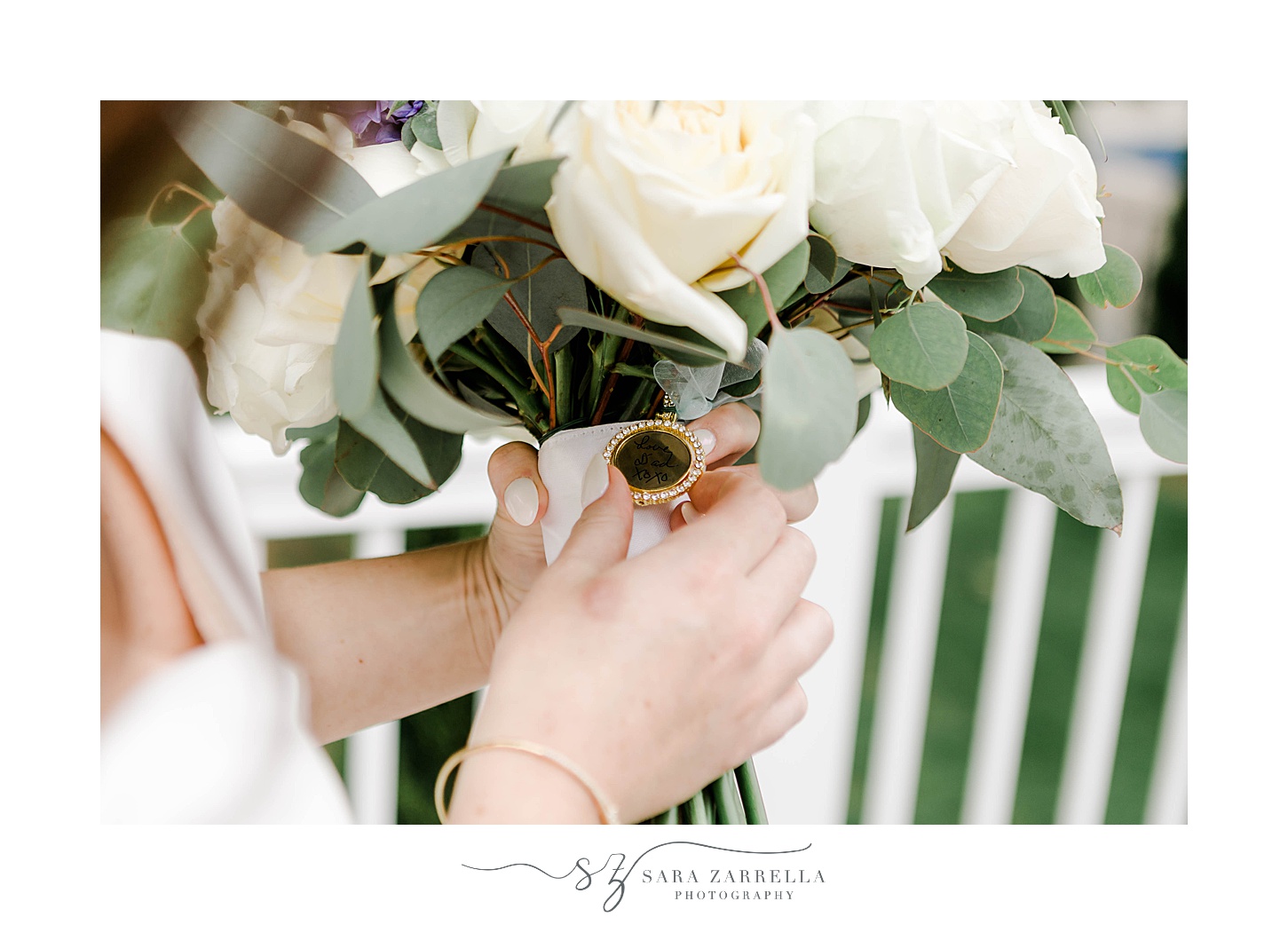 bride holds bouquet of ivory roses on back porch with charm