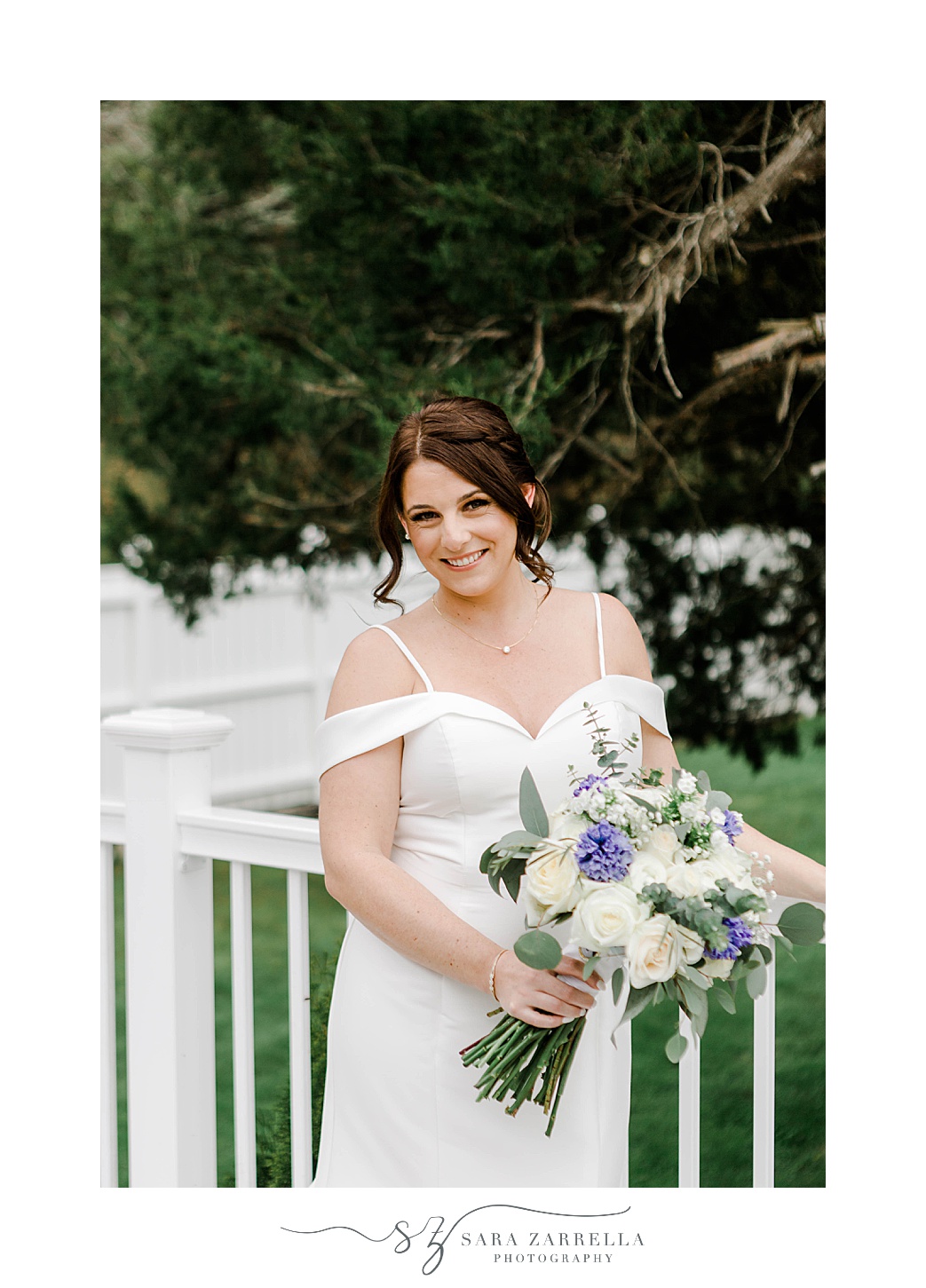 bride smiles in off-the-shoulder wedding gown with ivory and purple bouquet 