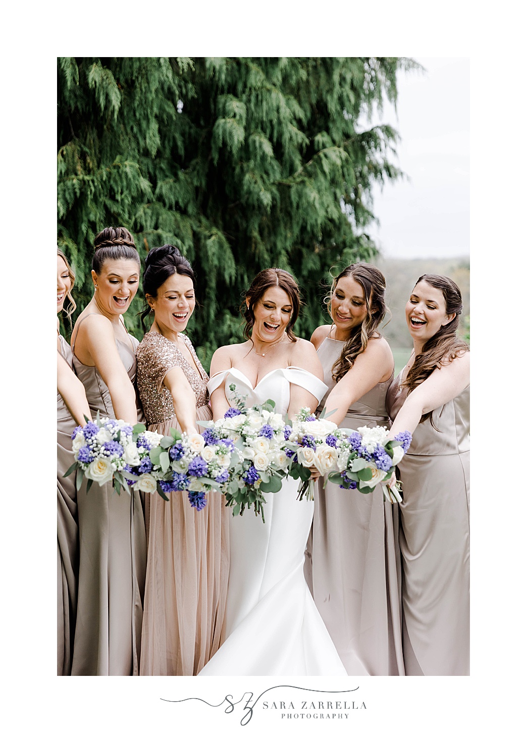 bride and bridesmaids hold out bouquets together in Lincoln RI