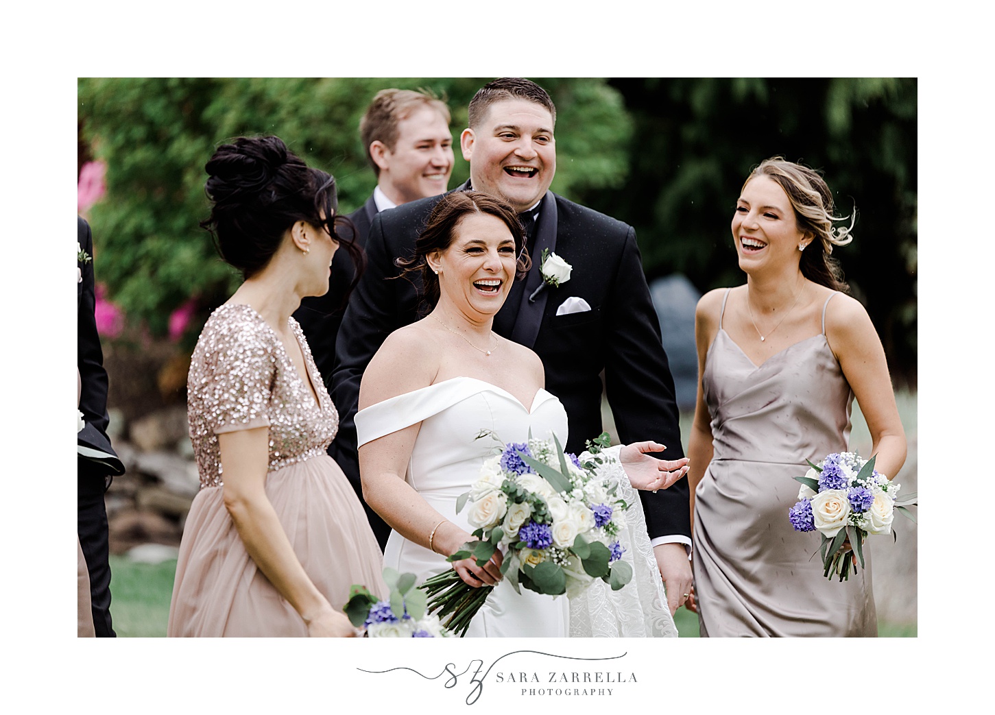 bride laughs with bridesmaids and groomsmen around her and groom