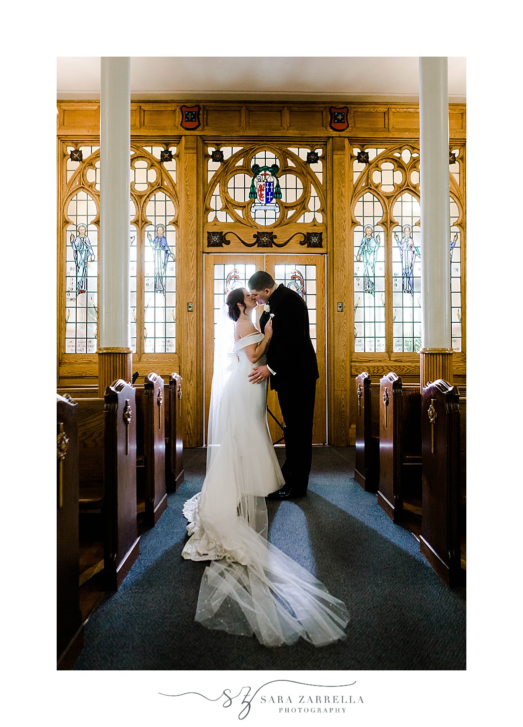 bride and groom kiss under stained glass window at Our Lady of the Rosary