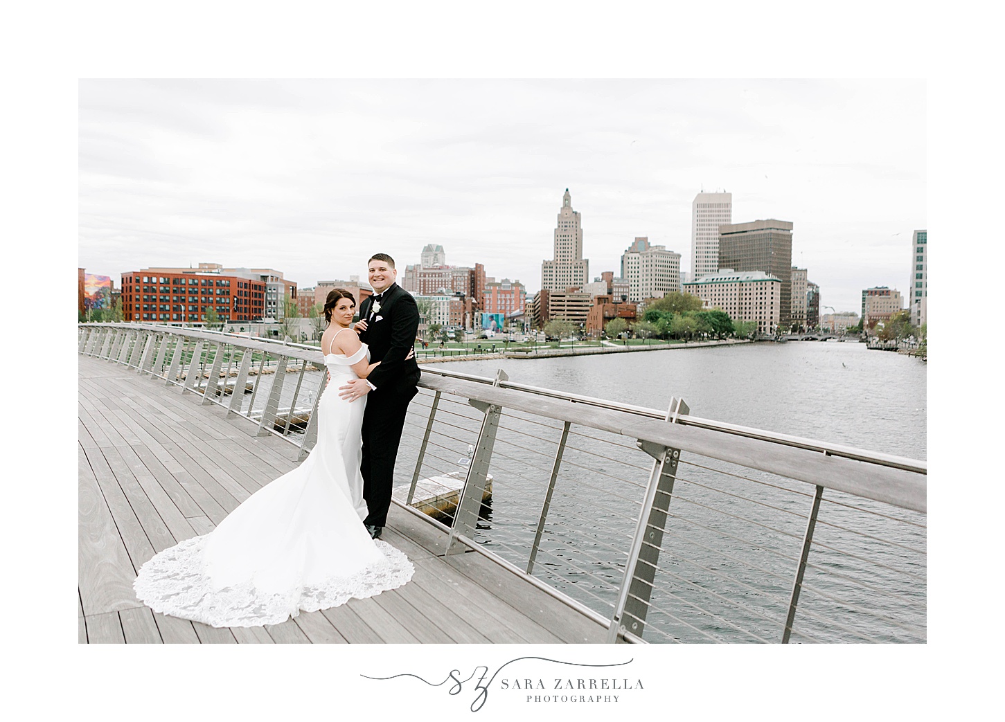 bride and groom hug leaning against the Providence Pedestrian Bridge
