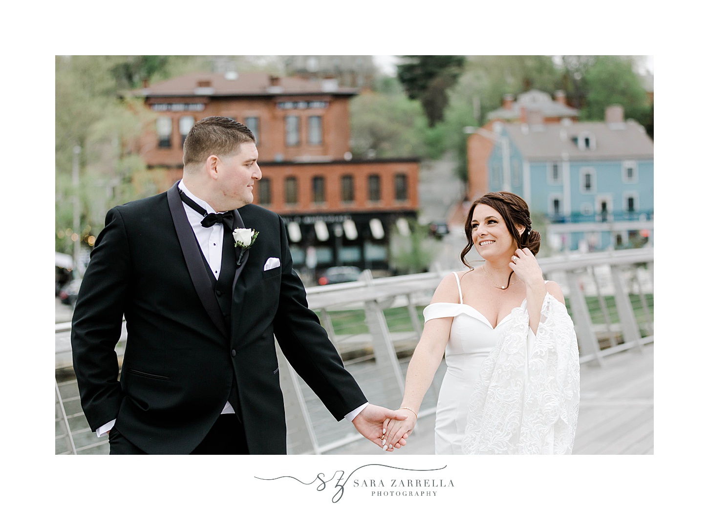 bride and groom hold hands walking on the Providence Pedestrian Bridge