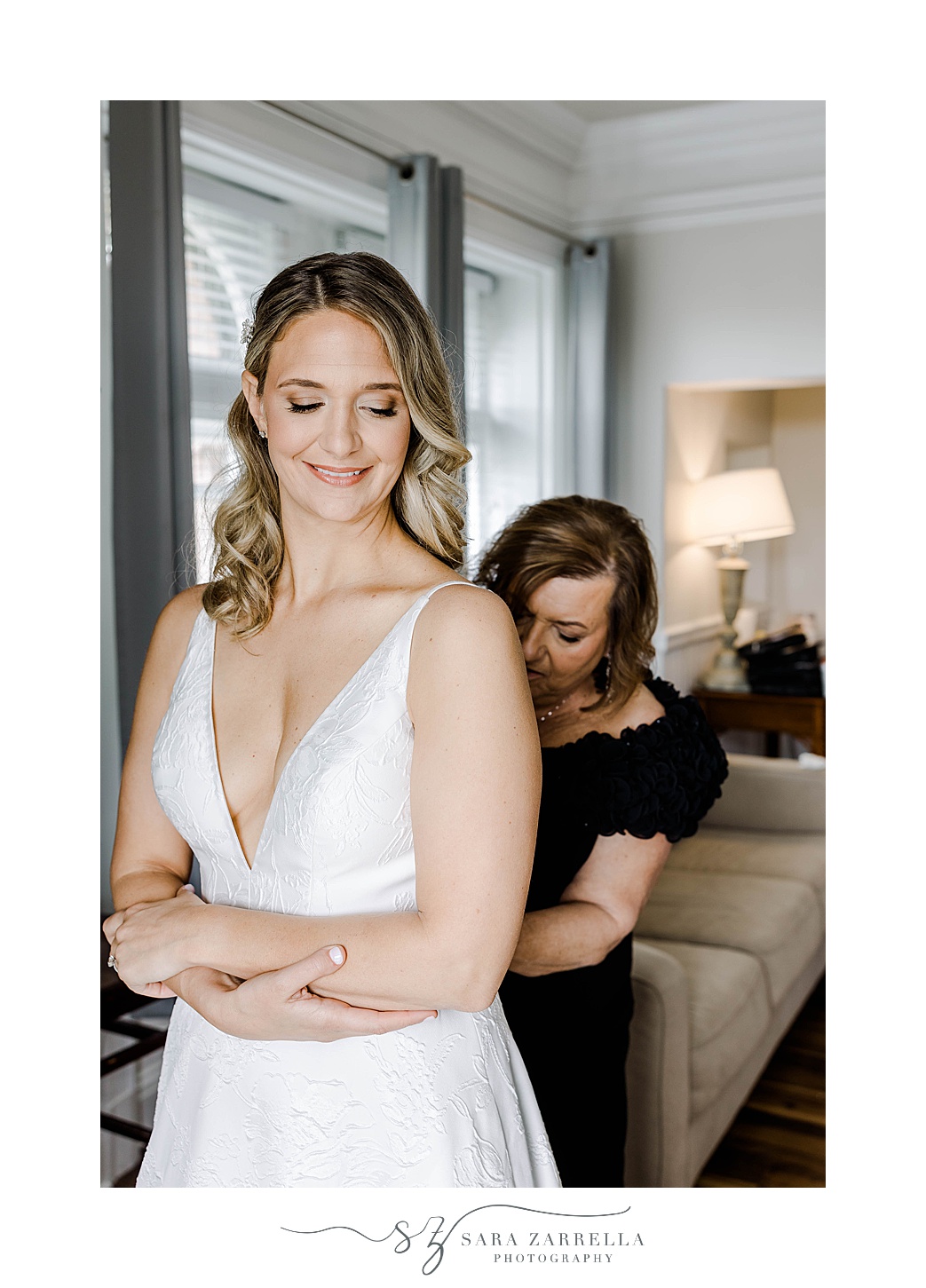 mother helps bride into wedding dress before OceanCliff Hotel wedding day