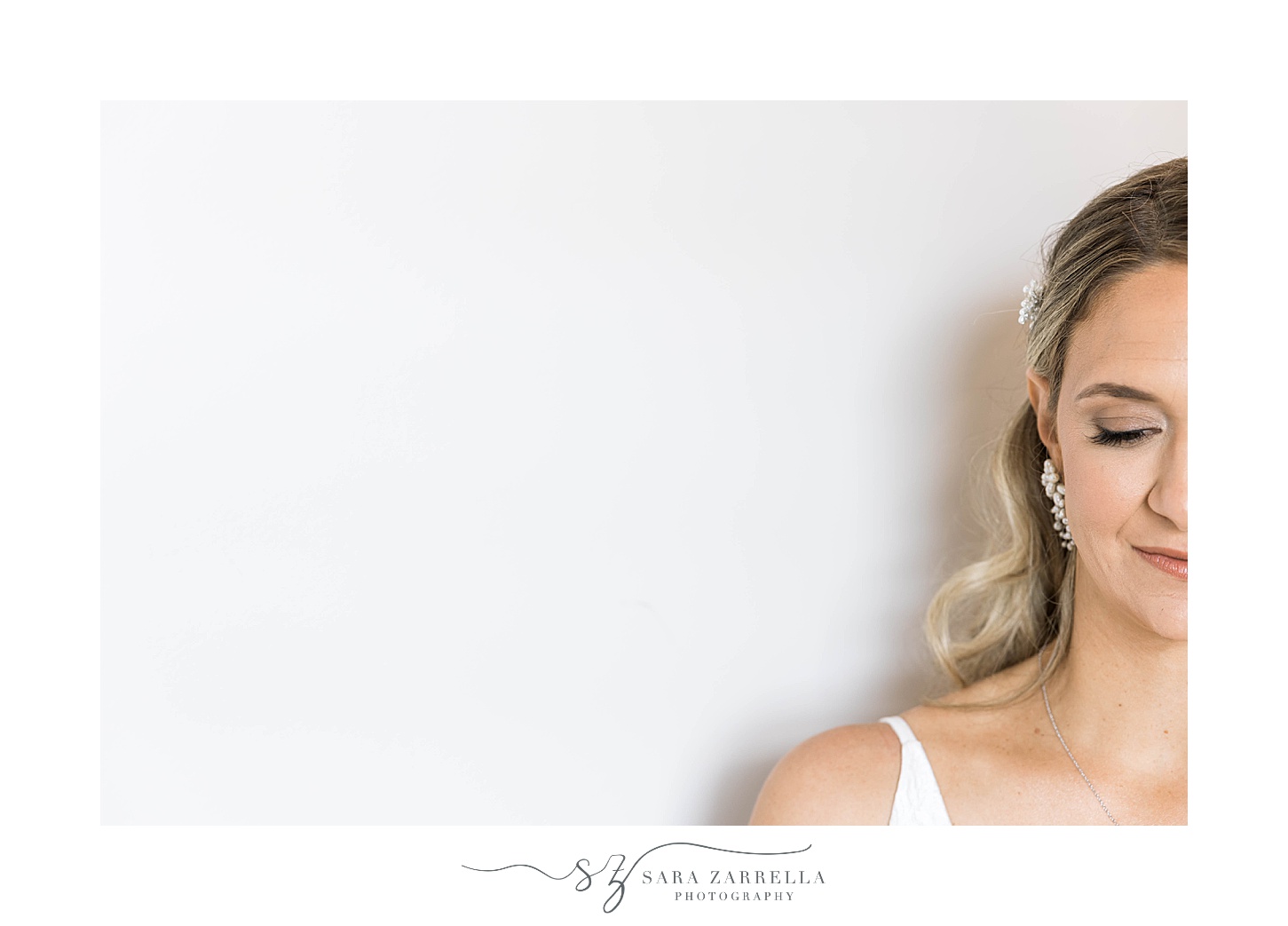 bride smiles against white wall at OceanCliff Hotel