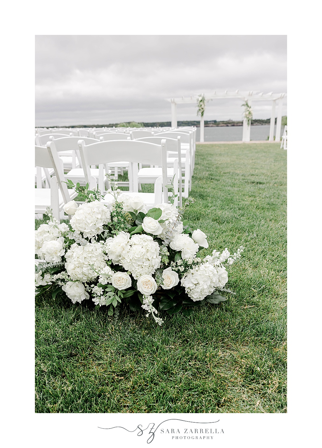 white flowers near chairs for ceremony along water on lawn at OceanCliff Hotel
