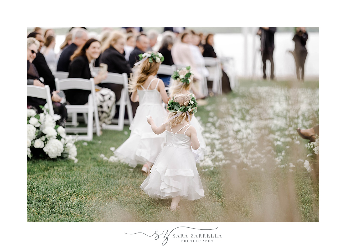 flower girls run down aisle in white dresses with flower crowns
