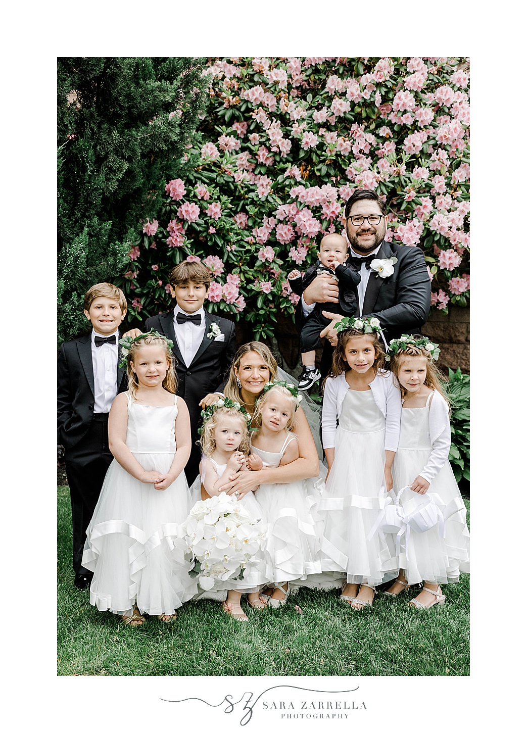 bride and groom pose with flower girls and ring bearers by pink flowers at OceanCliff Hotel