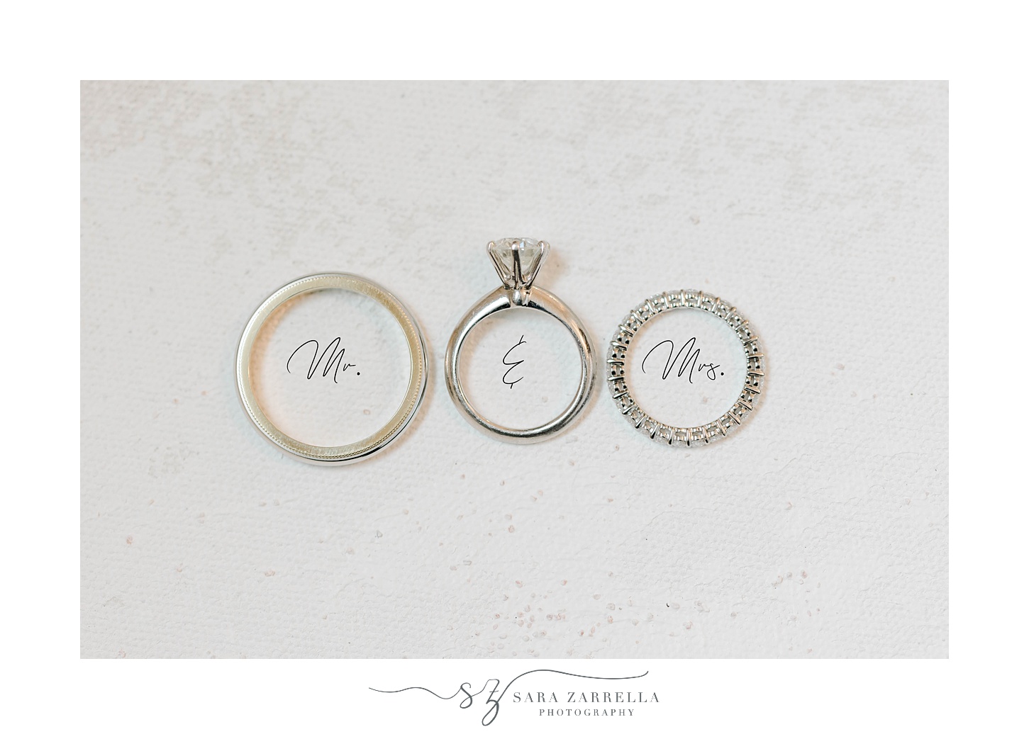 three wedding bands lay on ivory backdrop with Mr & Mrs underneath 