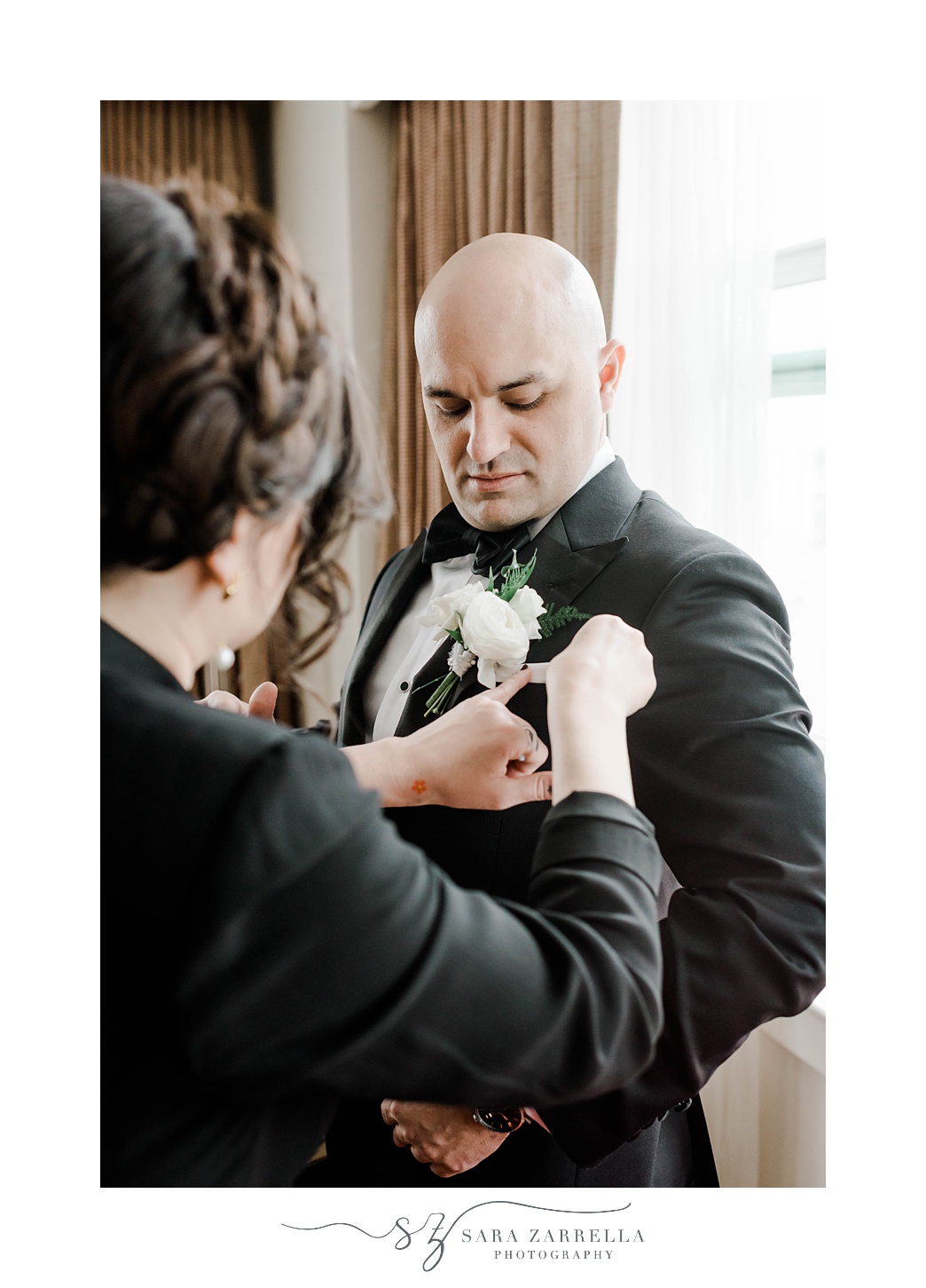 mom puts on boutonniere for groom