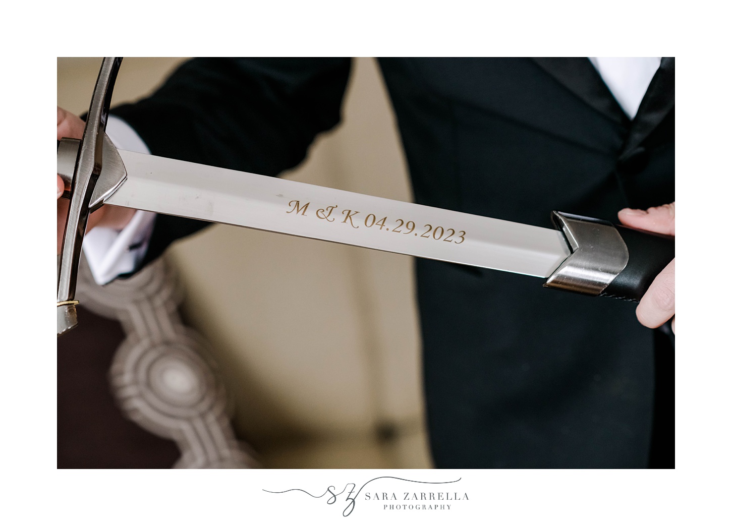 groom pulls saber out of case showing off engraving 