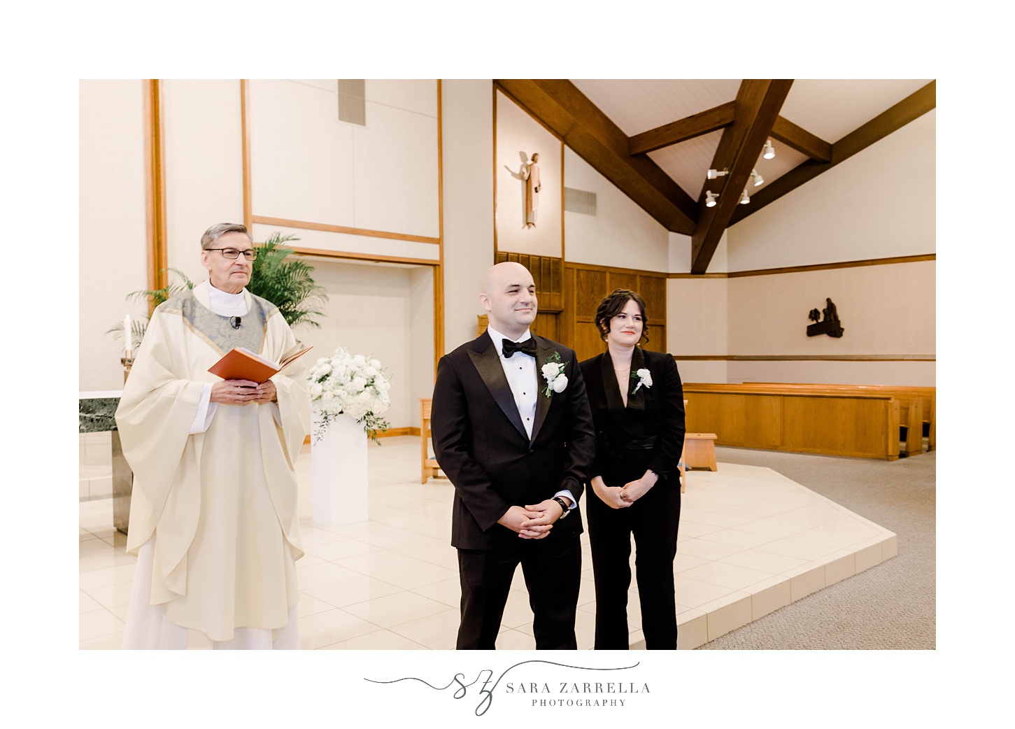 groom waits for bride at alter during wedding ceremony at St. Michael’s Parish in Smithfield
