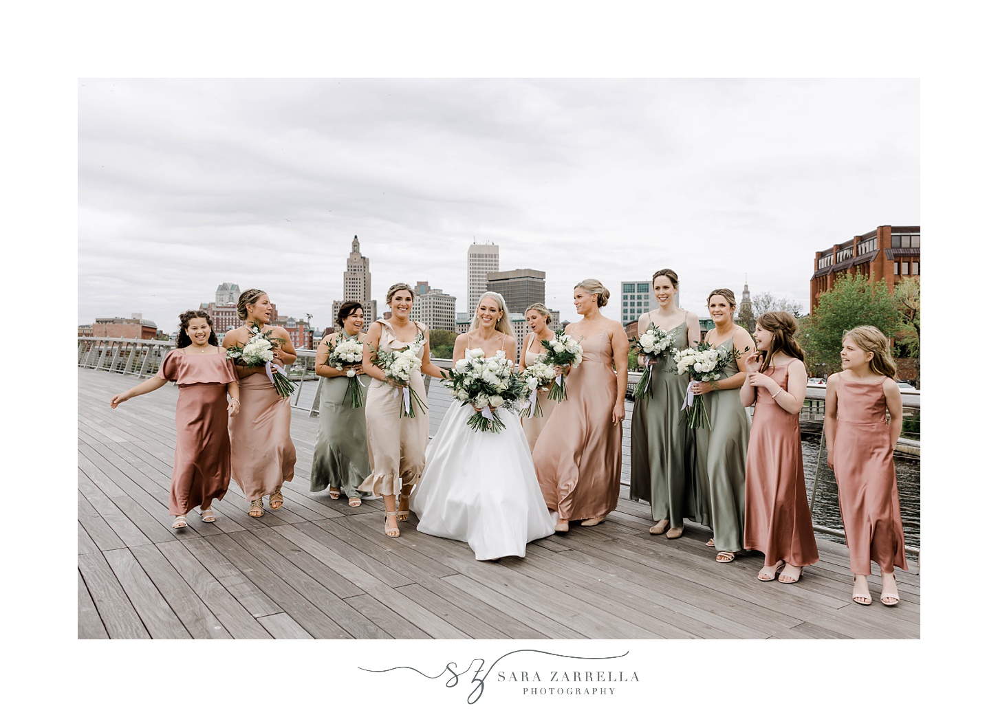 bride and bridesmaids in pink and green gowns walk on Providence pedestrian bridge