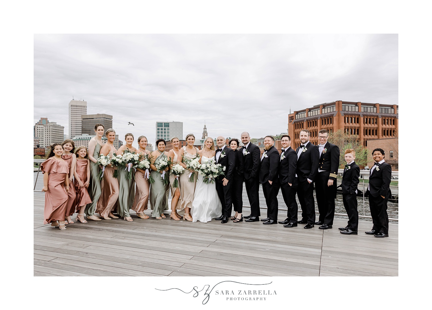 bride and groom pose with full wedding party on Providence pedestrian bridge