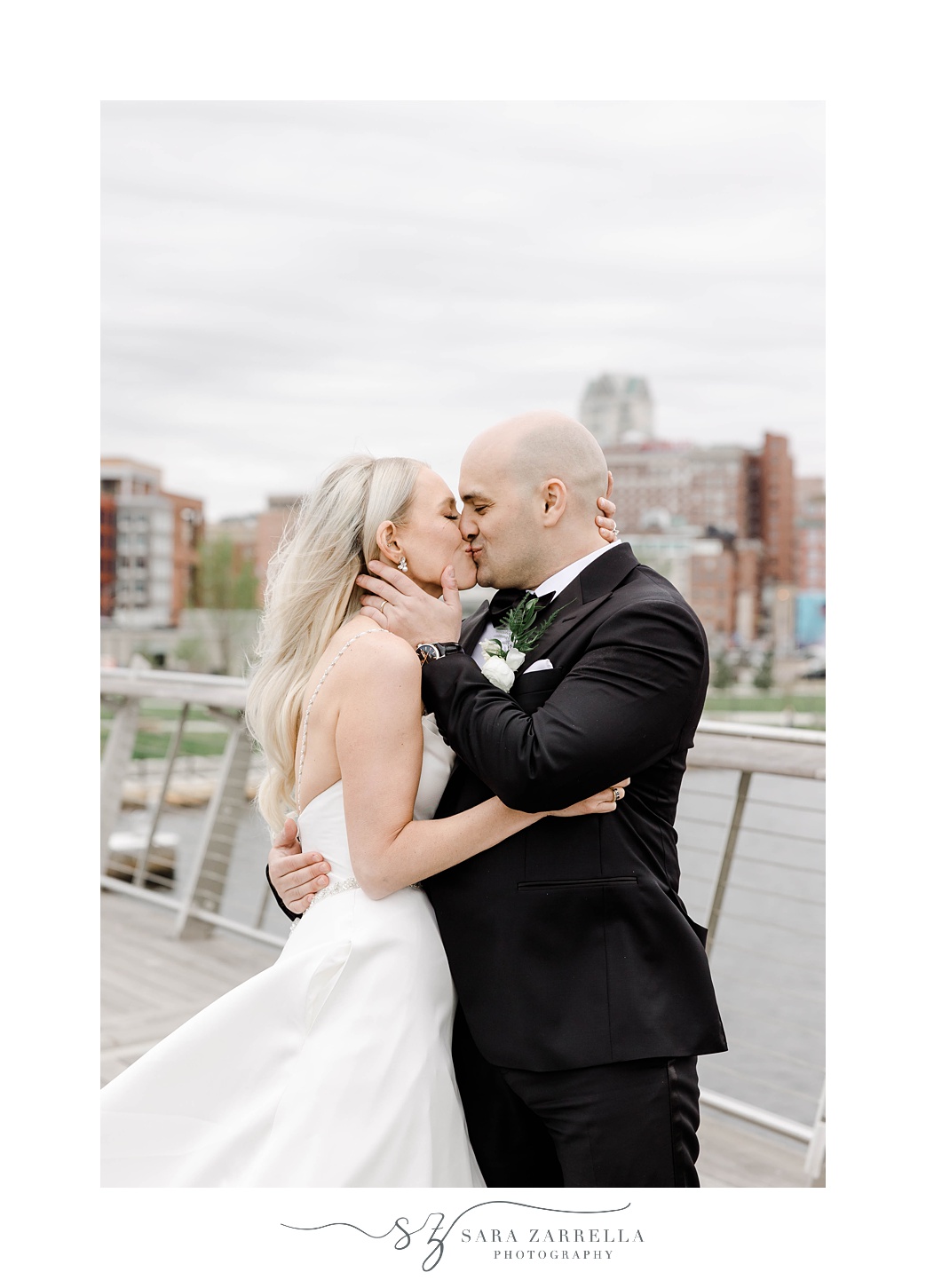 bride and groom kiss on the Providence pedestrian bridge holding each other's chins