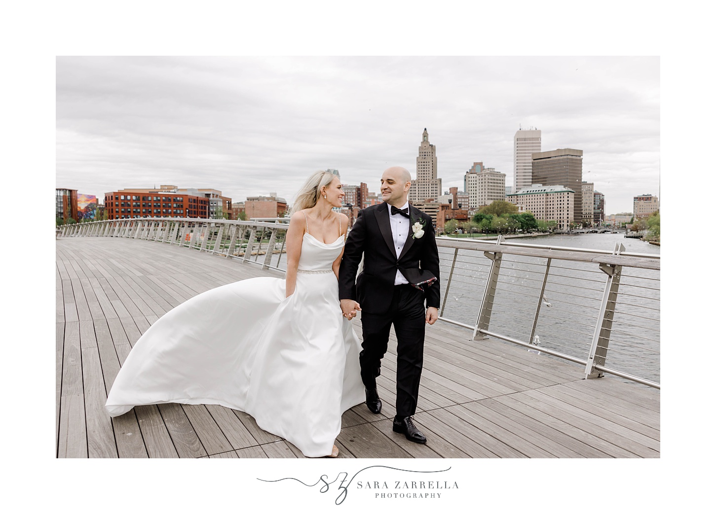 bride and groom hold hands walking on the Providence pedestrian bridge