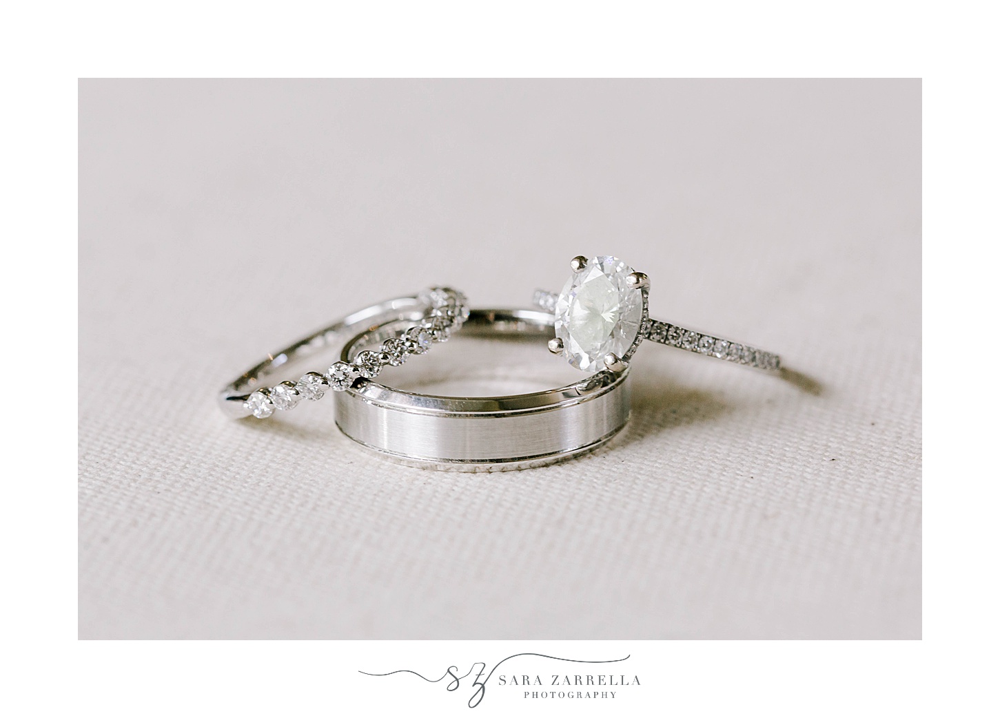two diamond rings lay on silver wedding band