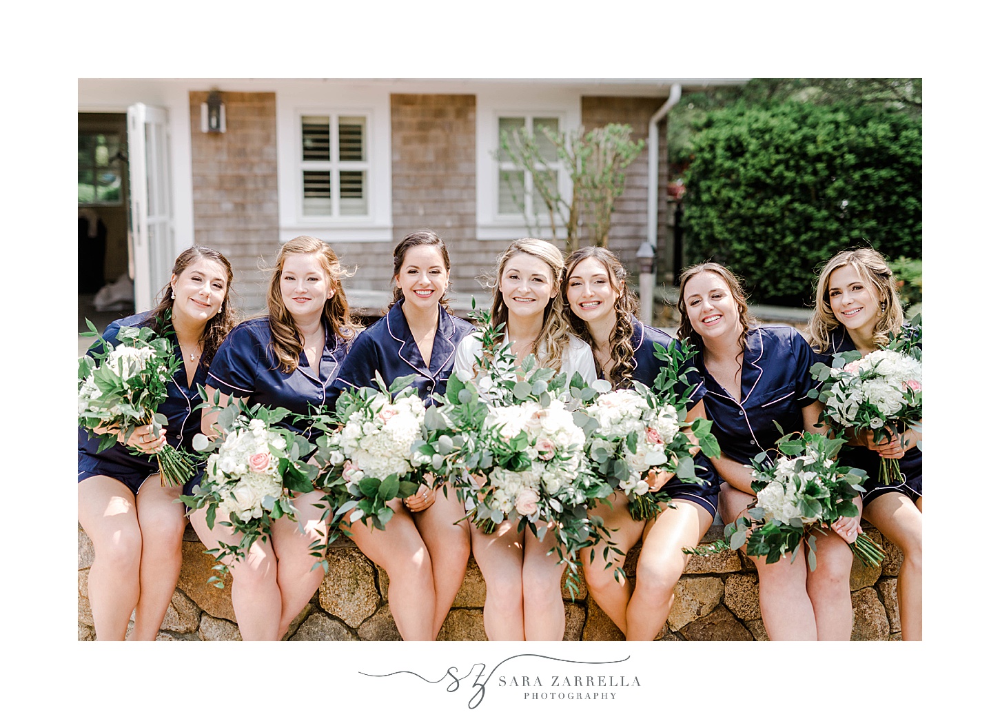 bride poses with bridesmaids holding ivory bouquet in Massachusetts 