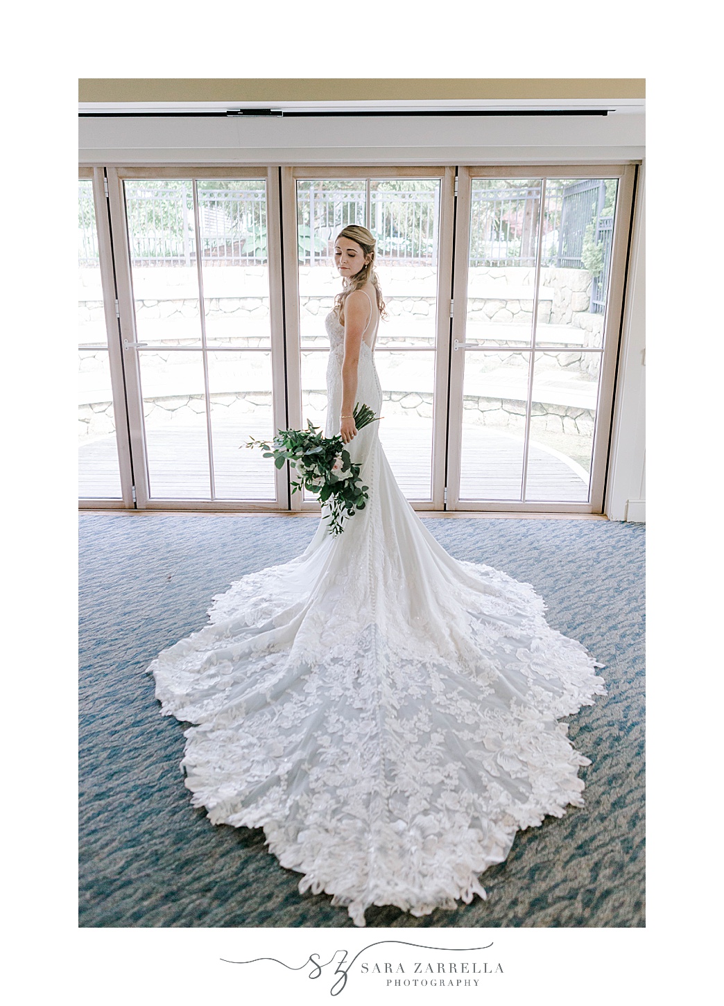 bride stands in window with train of dress laid out around her at Wequassett Resort