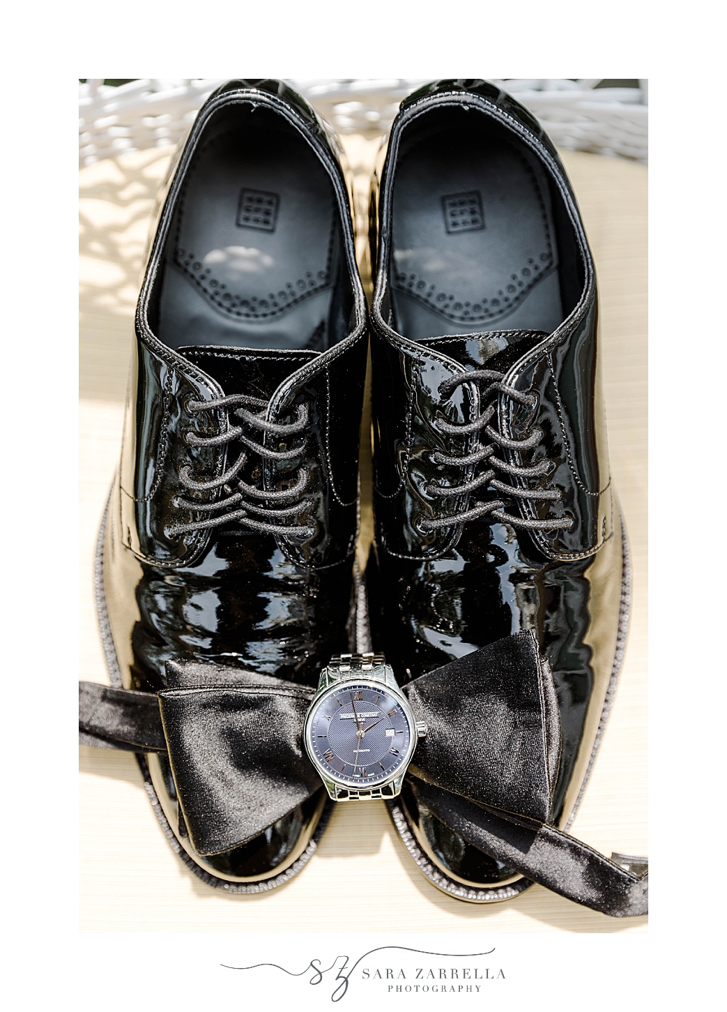 groom's shiny black shoes with watch and bow tie 