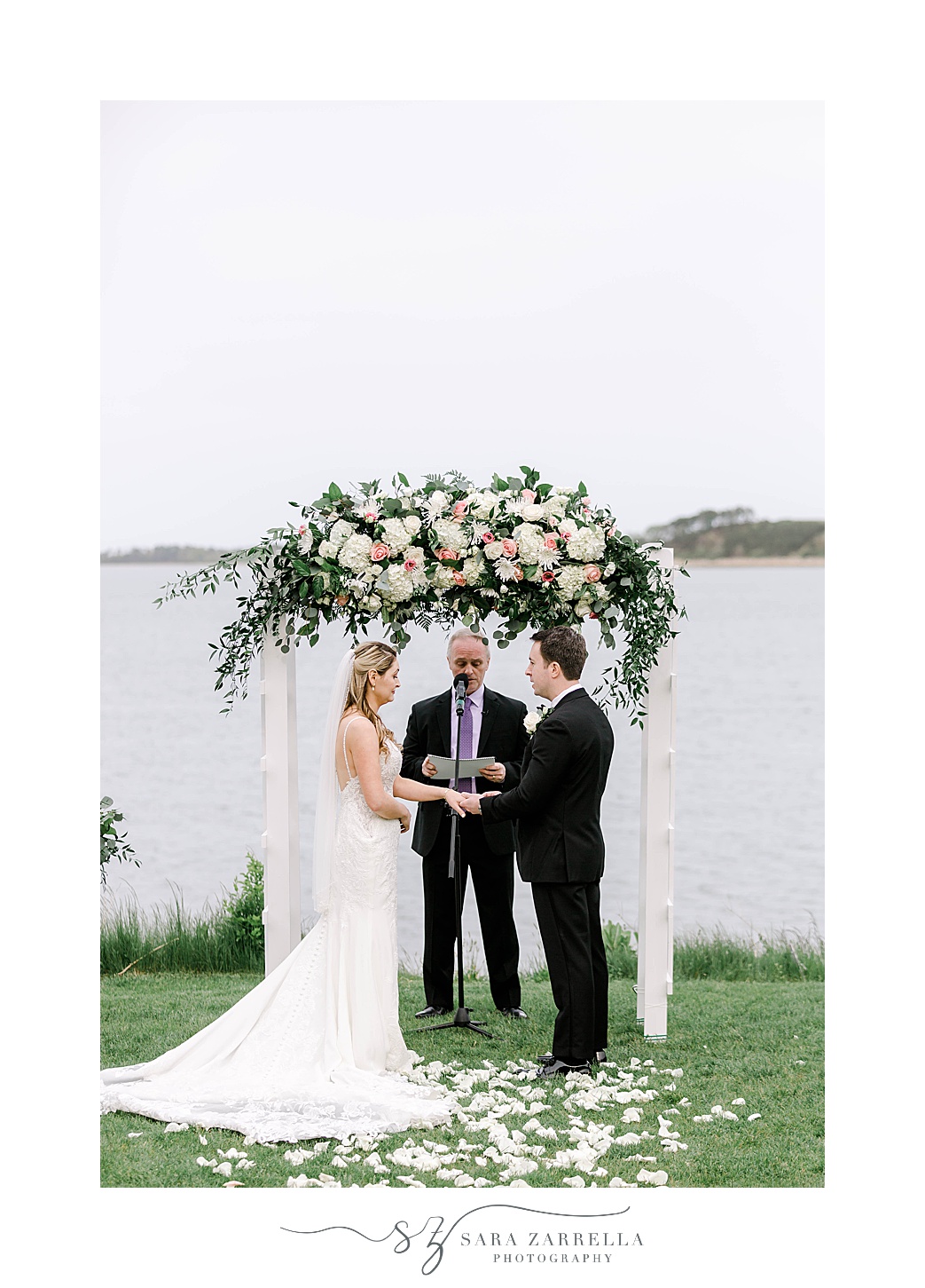bride and groom hold hands under floral arbor at Wequassett Resort