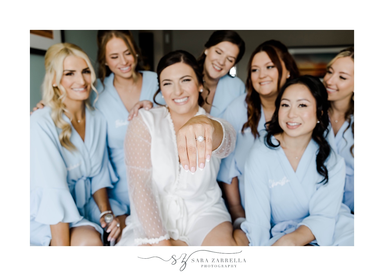 bride shows off wedding ring while bridesmaids sit around her