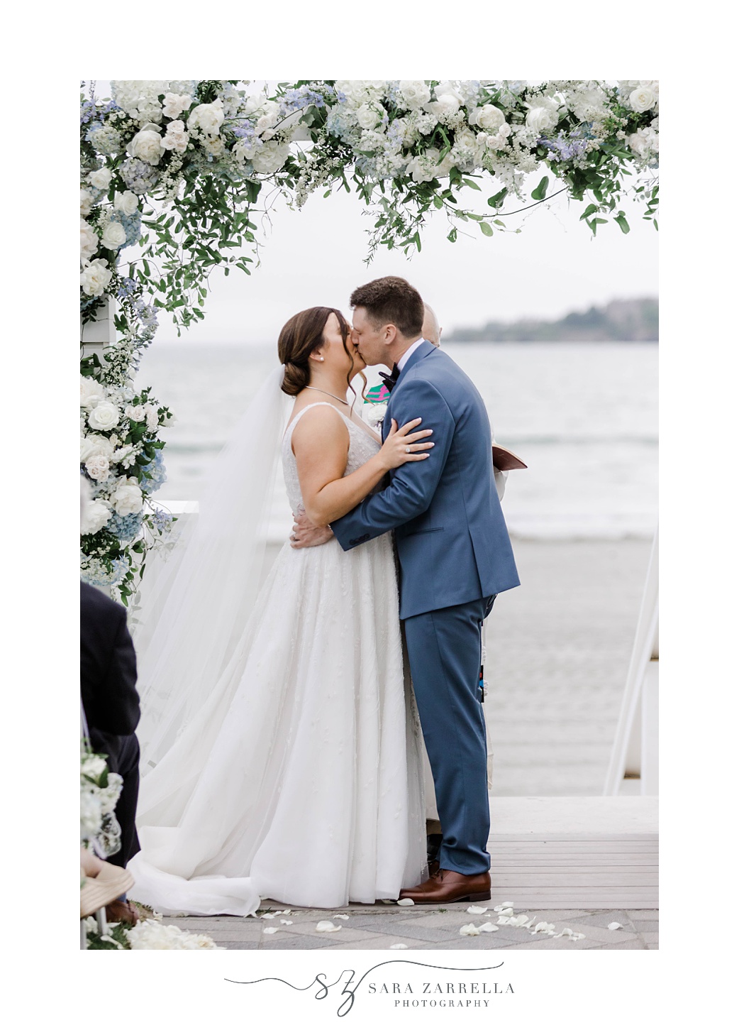 bride and groom kiss under arbor of white flowers at Newport Beach House wedding