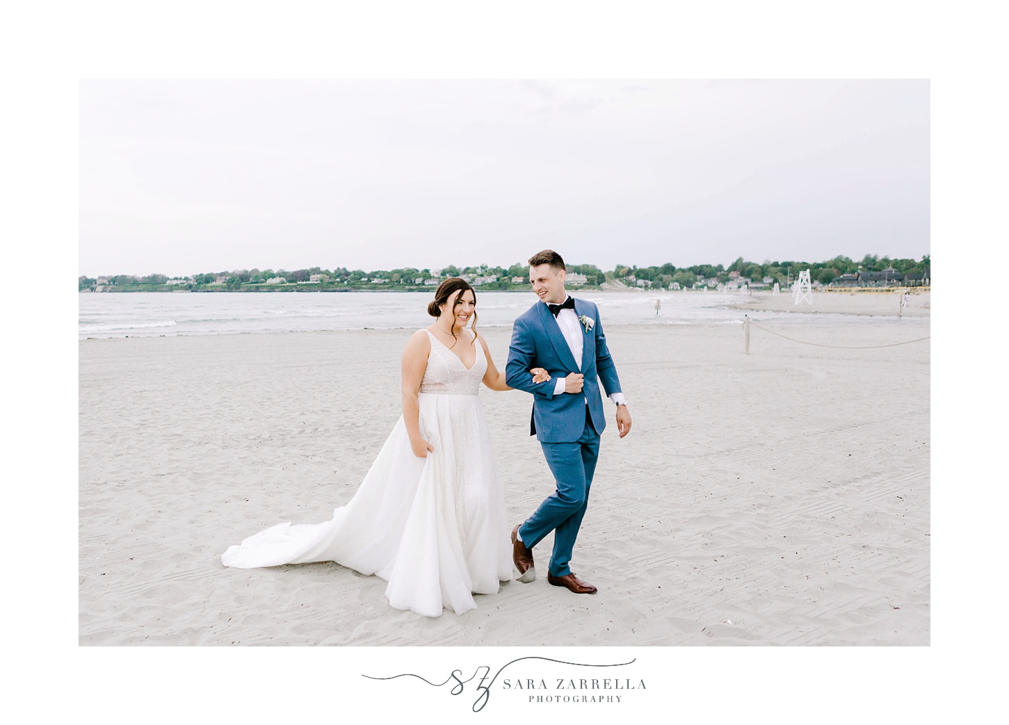 bride and groom walk along beach with bride holding groom's arm
