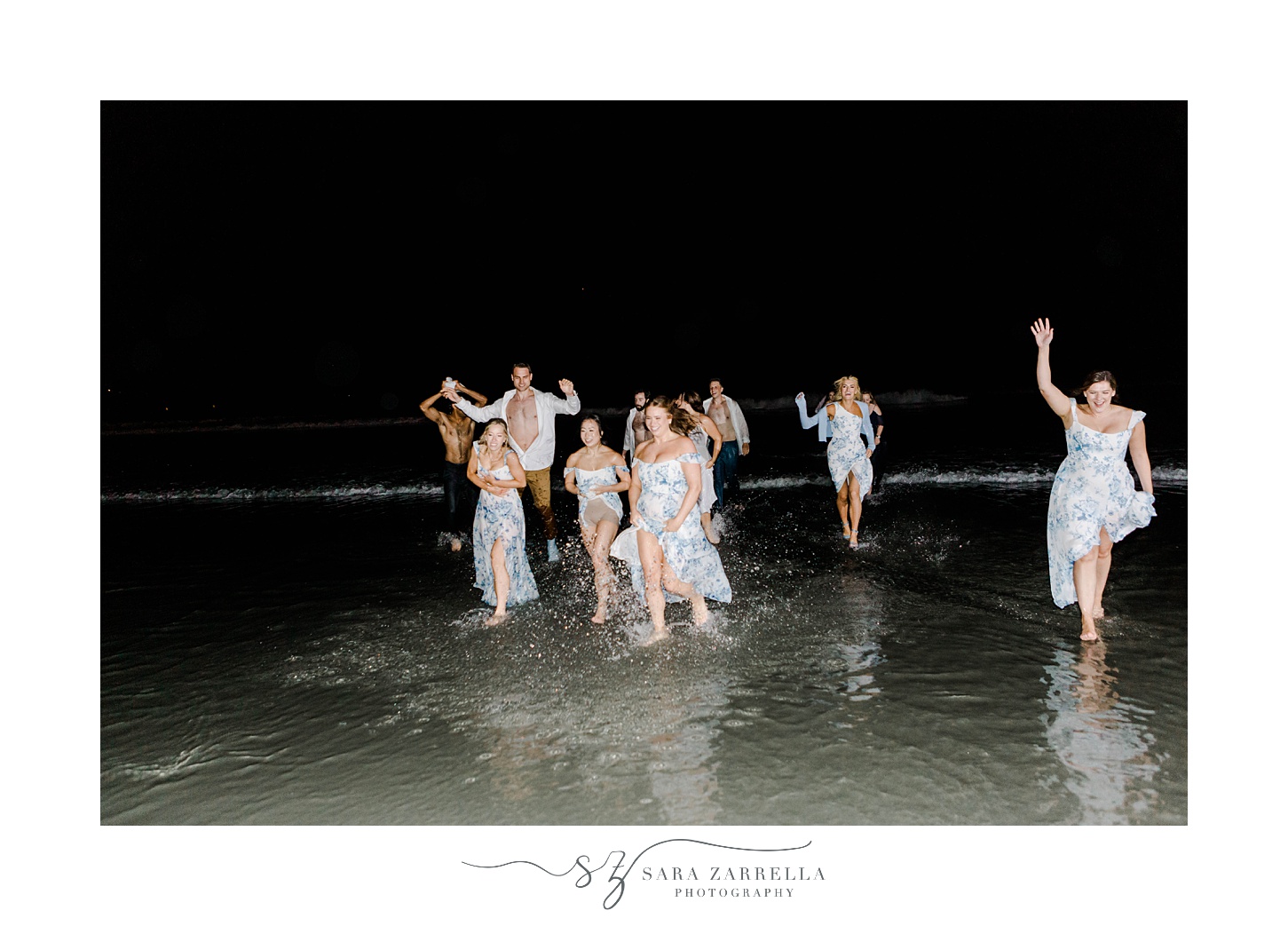 newlyweds run into ocean with bridesmaids in blue and white dresses