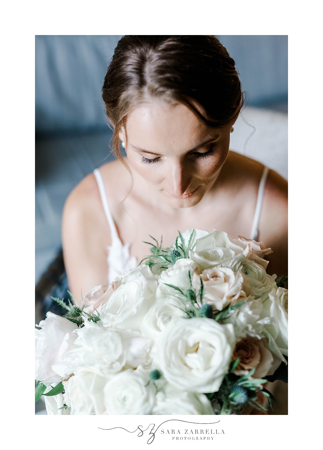 bride looks down at bouquet of ivory flowers at OceanCliff Hotel