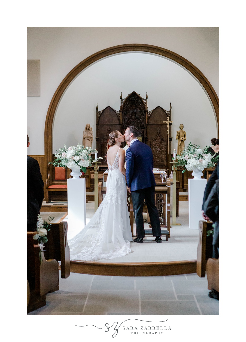 bride and groom kiss near alter during wedding ceremony at Our Lady of Mercy Chapel at Salve Regina University
