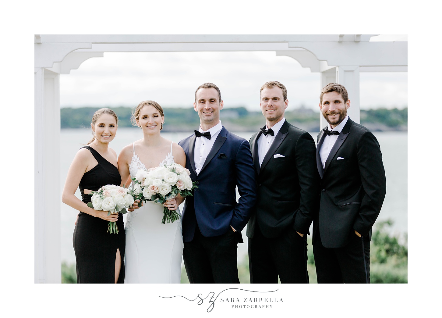 bride poses with groom, 2 groomsmen and bridesmaid near white alter at OceanCliff Hotel