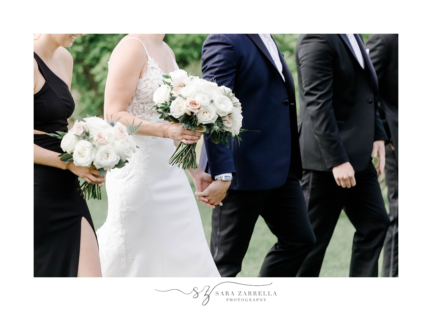 bride holds bouquet of white flowers walking with wedding party