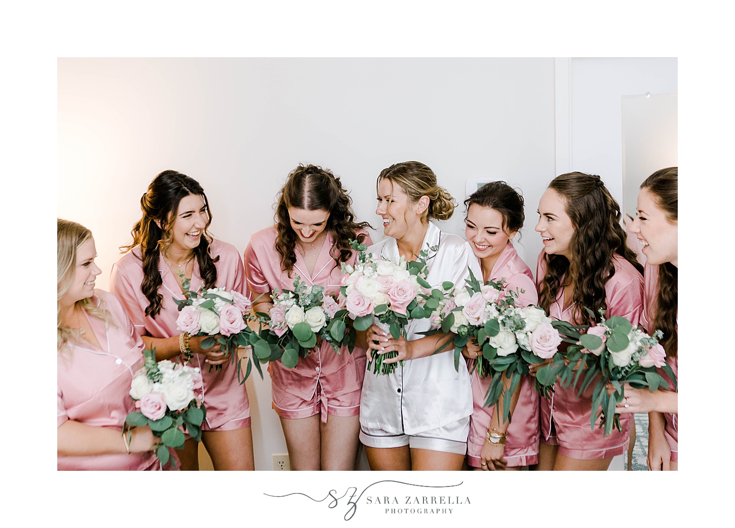 bride poses with bridesmaids in pink robes 
