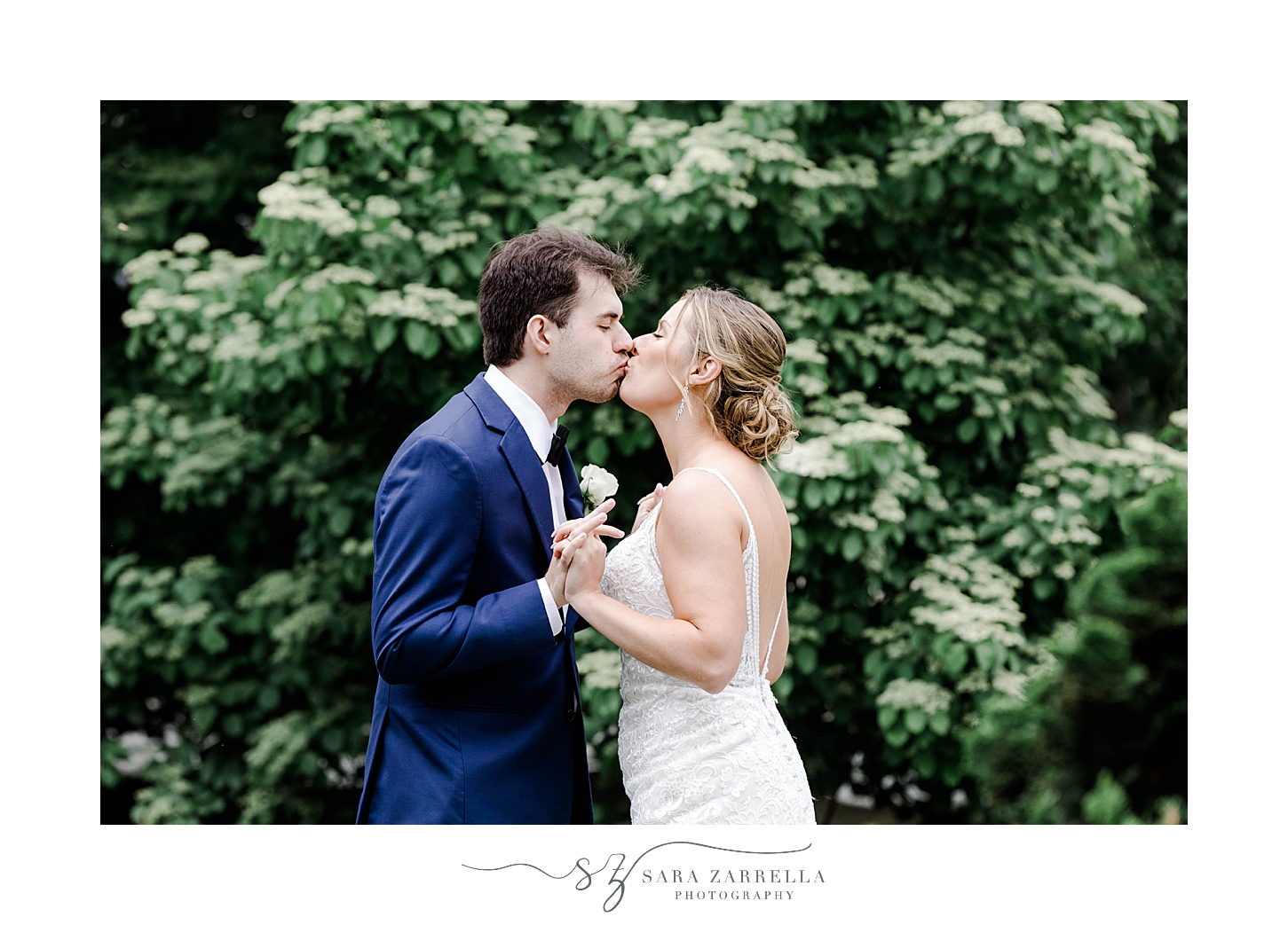 bride and groom kiss by greenery in Downtown Newport park