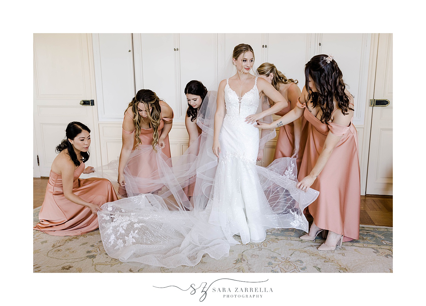 bridesmaids in pink gowns help bride with wedding dress and veil