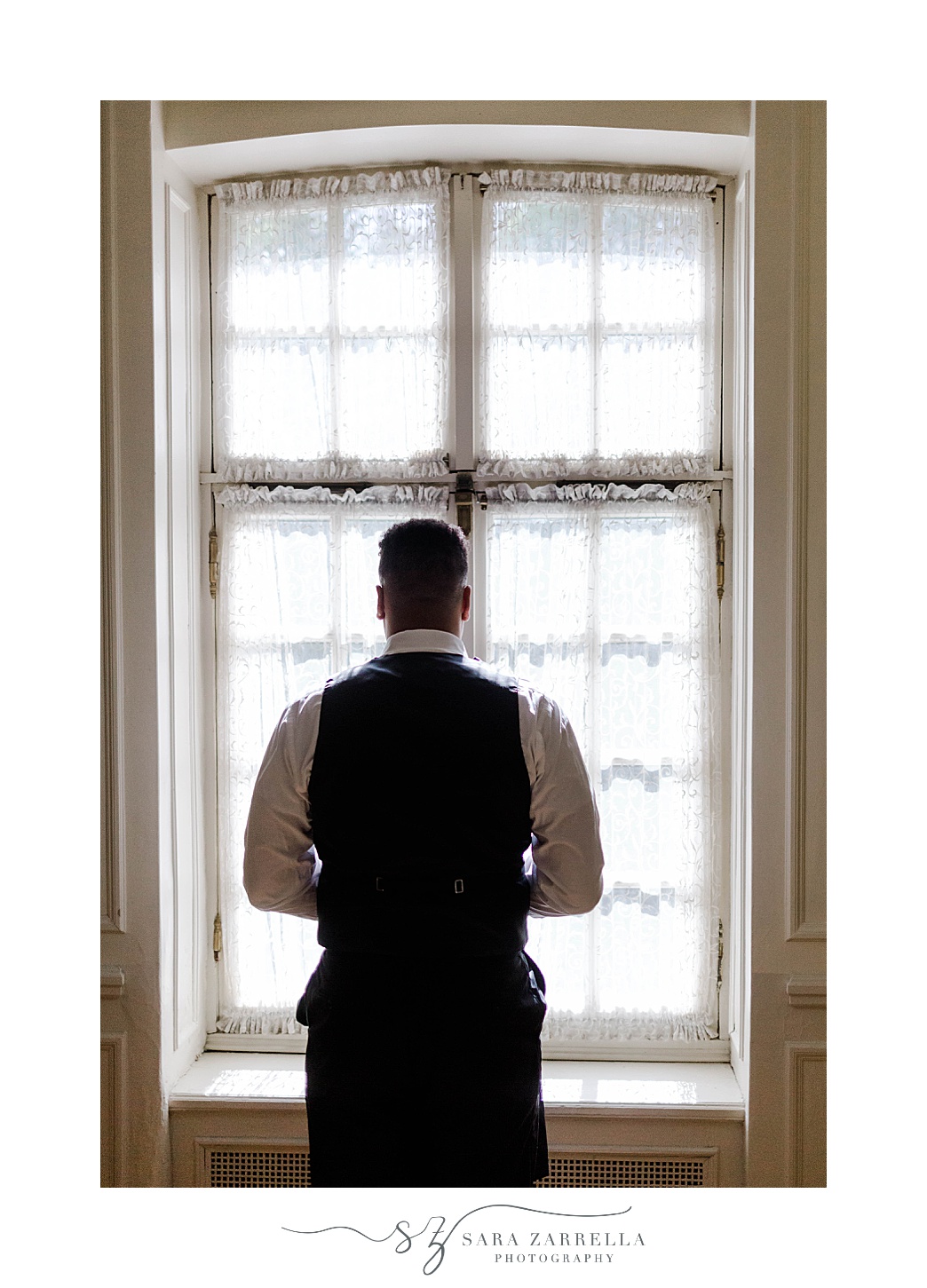 groom prepares for wedding day looking out window at Glen Manor House