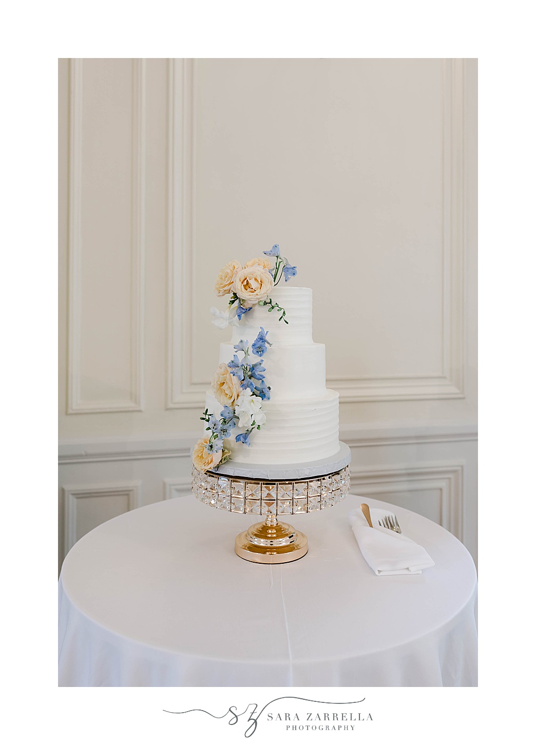 tiered wedding cake with peach and blue flowers 